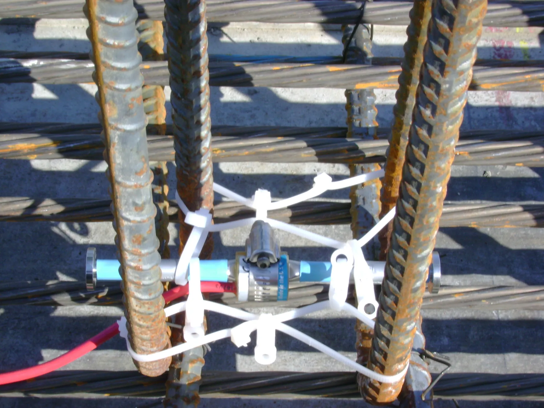 Vibrating-wire strain gauge tied to reinforcing bars before concreting